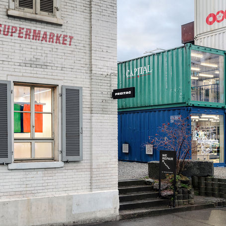 FREITAG Repair Station in Zürich mit markanten Containerbauten und Werkstatt im Hintergrund. Eingang mit «We Repair»-Hinweis, Standort neben dem FREITAG Flagship Store in der Geroldstrasse.