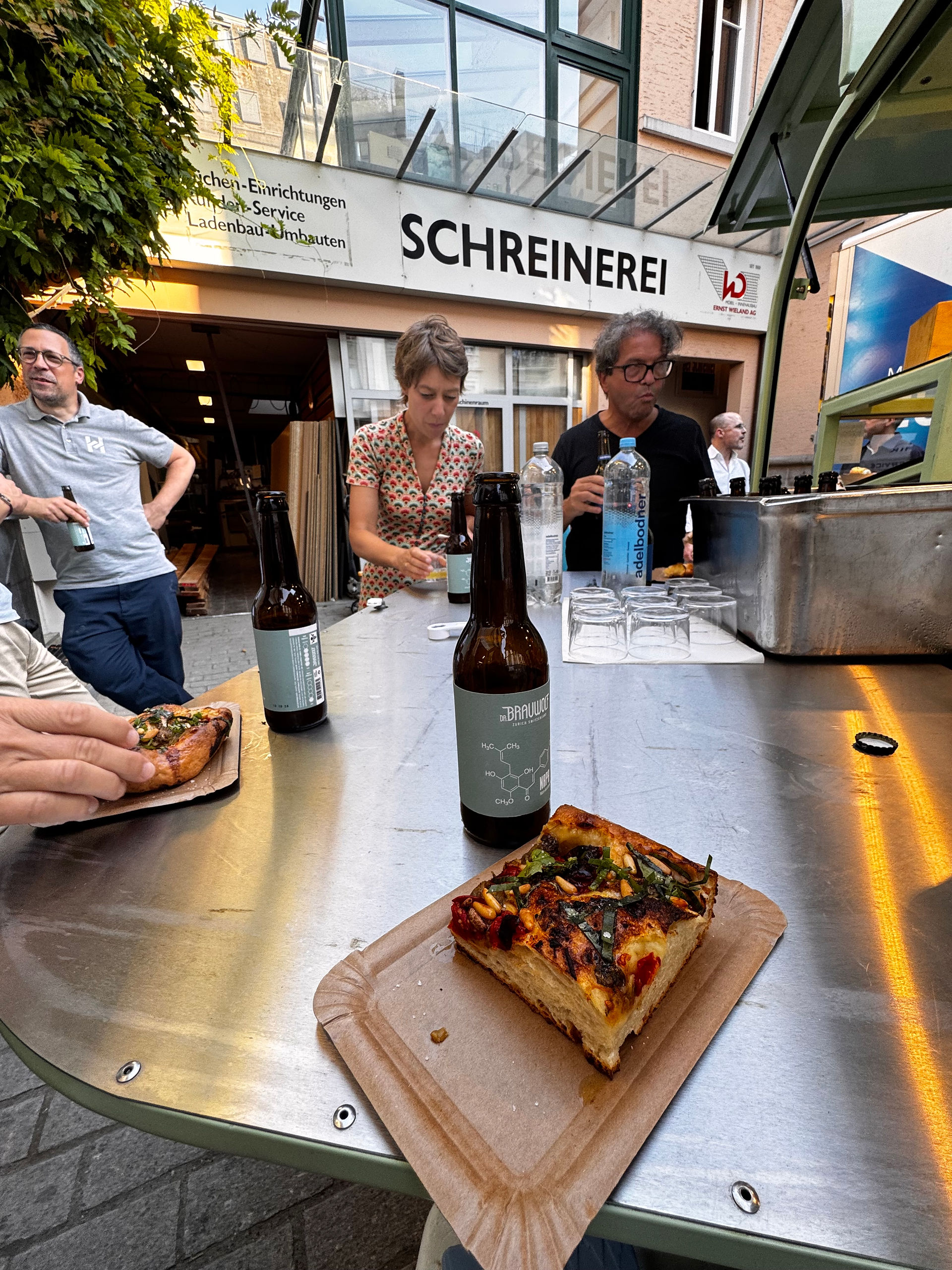 Stück Focaccia auf einem Holzteller, daneben eine Flasche Bier von Dr. Brauwolf.