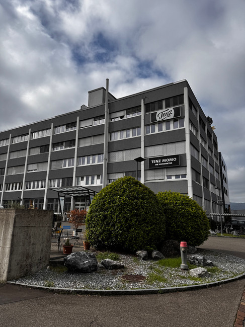Aussenansicht der Momofaktur von Tenz Momo in Schlieren mit Firmenlogo am Gebäude.