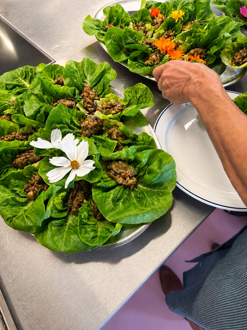 Frisch angerichtete Salatblätter mit Füllung und essbaren Blüten auf grossen Platten.