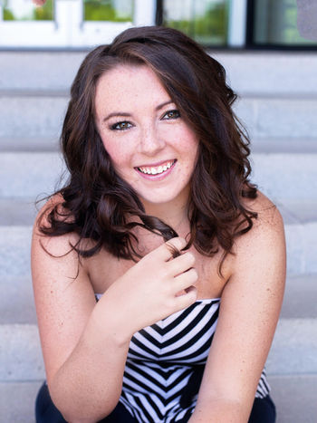 Professional Headshot of an actress wearing a black and white top sitting at the top of the stairs.