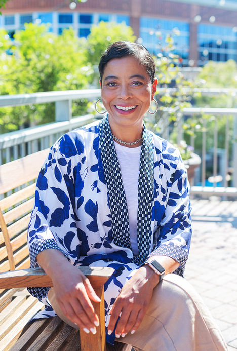 photography by A Brew & You Headshots in Charlotte of woman in floral blouse sitting in city with backlight.