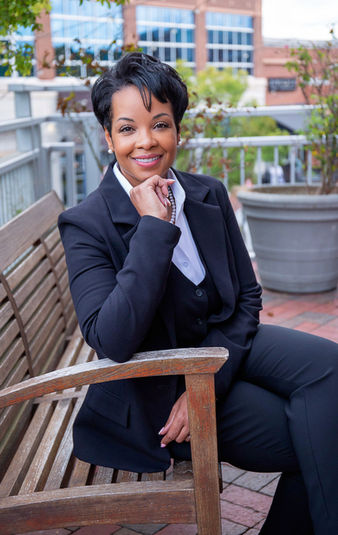 A professional photoshoot by A Brew and You of a business woman in a black suit sitting on a park bench in Ballantyne Commons, NC