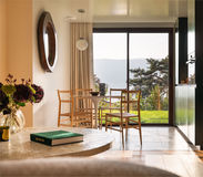 Salle à manger moderne et lumineuse avec baie vitrée, mobilier design en bois clair et vue panoramique sur jardin et montagne – photo d’architecture intérieure Studio Bergoend
