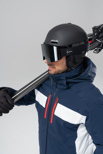 Homme en combinaison bleue avec casque et skis sur l’épaule