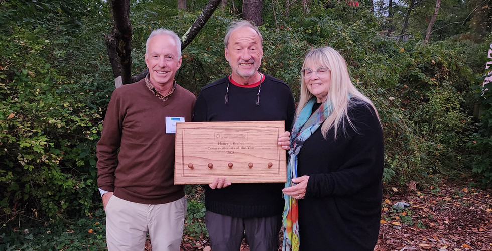 Three people posing  an award.