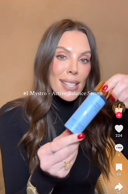 a woman is holding a bottle of active balance serum