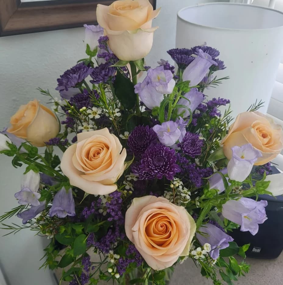 Whimsical floral arrangement with dark purple mums and peach roses