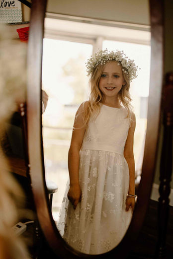 Little girl with a handcrafted baby's breath flower crown, standing at a wedding venue
