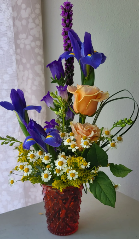 Garden-inspired bouquet with daisies, peach roses, irises, and lavender-like stems