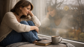 Woman sitting by a window in a quiet reflective moment, representing subtle grief, emotional processing, and life transitions