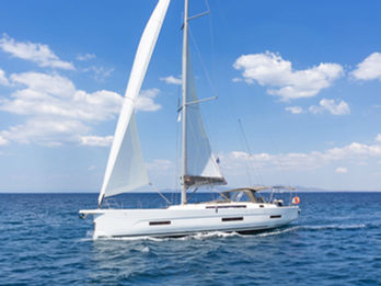 Dufour 530 sailing toward the camera under full sails, aerial forward view, Aegean blue waters.