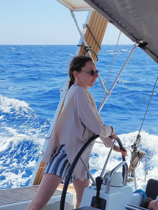 Woman smiling at the helm, enjoying the thrill of steering, Salty Fundamentals course.