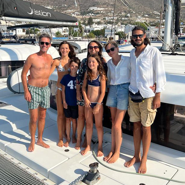 Photo of guests and skipper on the bow of our catamaran at the end of the Epic Voyage experience in the Cyclades.