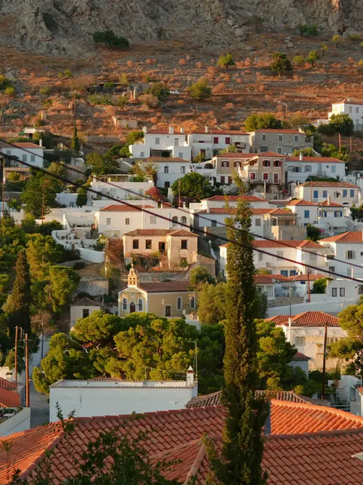 Golden hour view of Hydra with traditional tiled‑roof houses, warm light, part of La Dolce Vita journey.