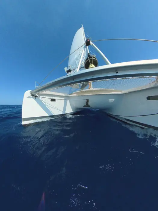 Catamaran approaching from waterline view, full sails, fast sailing, Catamaran Confidence course.