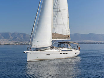 Jeanneau Sun Odyssey 519 sailing toward the camera under full sails, aerial forward view, Aegean blue waters.