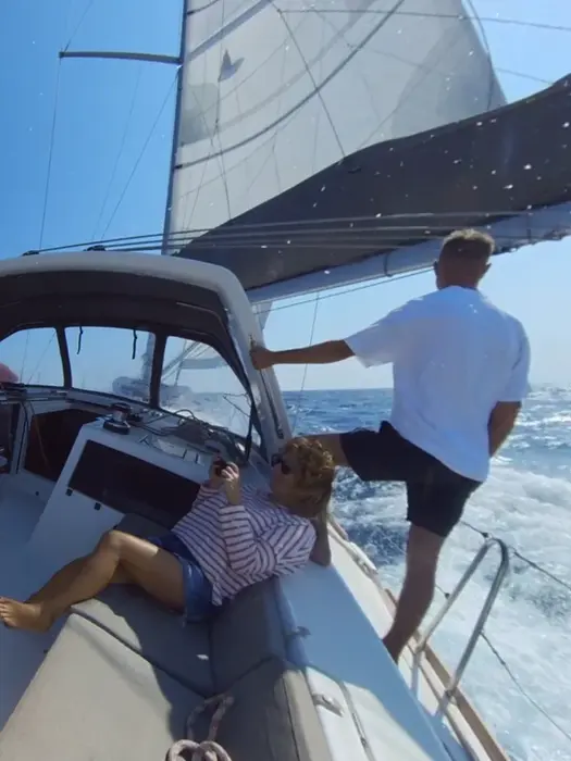 Man bracing on leeward side, second reef in main sail, focused ahead, Salty Fundamentals heavy air practice.