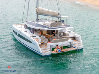 Fountaine Pajot FP41 at anchor, stern view with couple relaxing on swim platform, turquoise water.