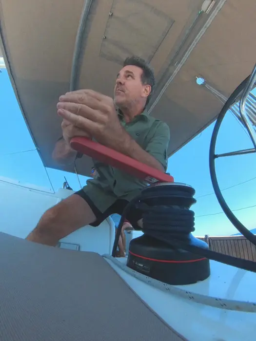 Man trimming sail with winch, focused on the sails, Salty Fundamentals hands‑on training.