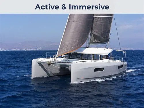 Aerial side view of an Excess 12 performance catamaran sailing with purpose, minimal wake, clear water.