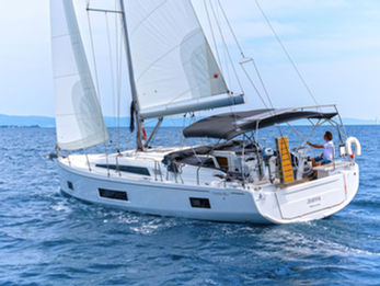 Beneteau Oceanis 46.1 seen from astern under full sails, aerial view, white wake trailing.