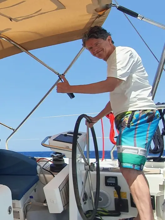 Man laughing at the helm, looking toward camera, confident steering on Salty Fundamentals.
