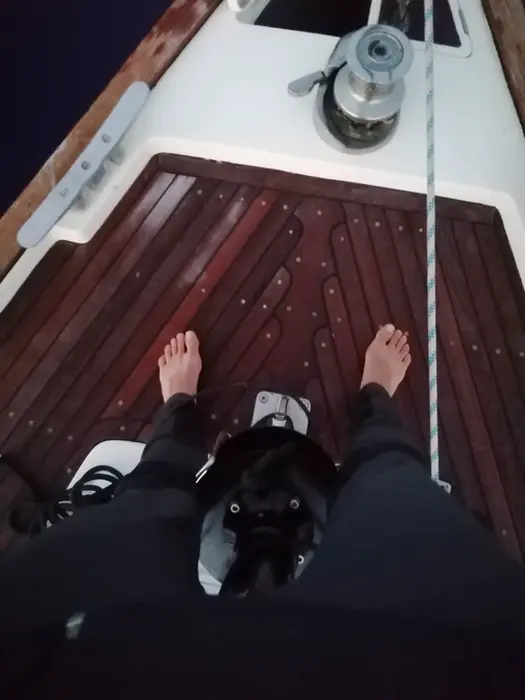 Crew member photographing her legs, artistic shot during anchoring prep, Docking Drills moment.