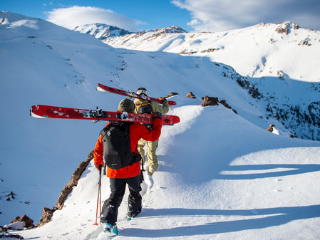Two skiers bootpacking along a ridge in the high mountains