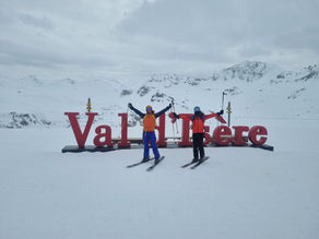 Two skiers posing in front of a Val d'Isere wordmark sign, Val d/'Isere, France