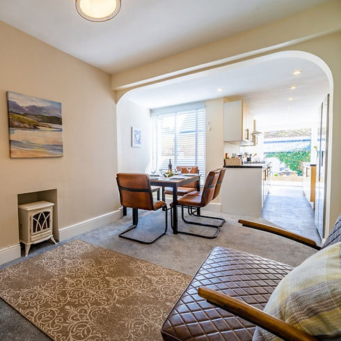 Cozy open plan dining area with leather chairs pattern rug small stove