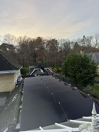Rooftop covered with dark solar panels under a soft, cloudy sky