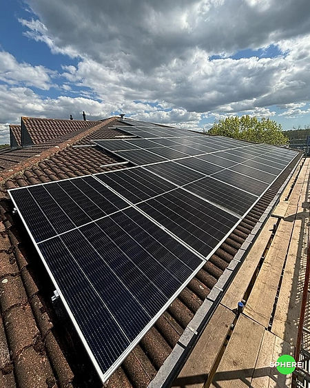 Solar panels installed on a tiled roof under a partly cloudy sky