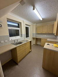 Long kitchen during renovation with fitted wooden base units and a stainless steel sink