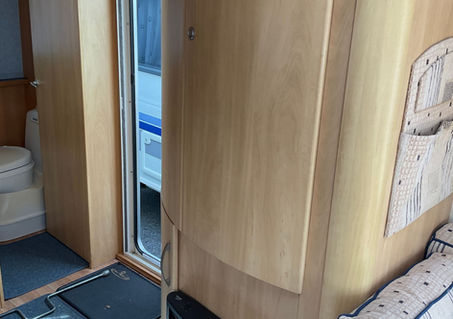 Caravan kitchen featuring a gas cooker, circular sink and light wood cabinetry