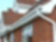 Red brick house with white framed windows and brown tiled roof