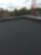 A flat rooftop covered with dark gray material