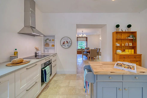 Modern light kitchen with wooden island unit and view into dining space