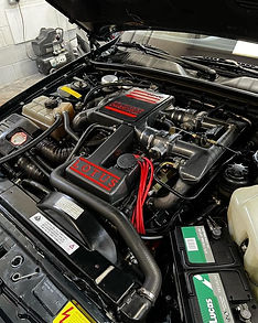 Close-up of a Lotus engine in a car with red accents and various components