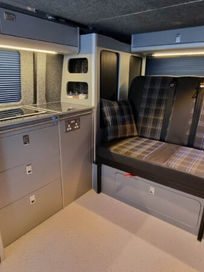 Sleek grey campervan galley kitchen unit featuring modern doors and a fitted bench seat