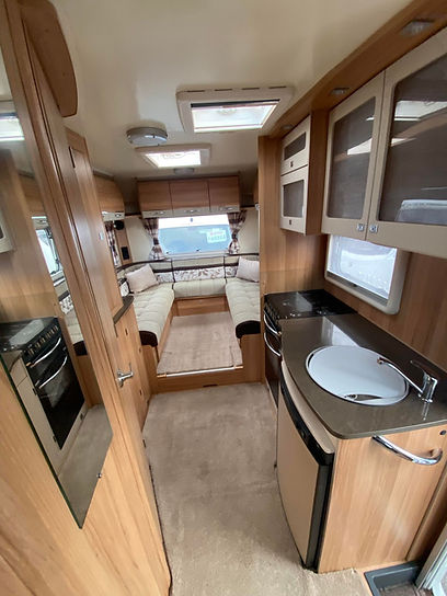 Interior of a cozy wooden caravan featuring a compact kitchen