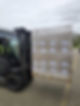A forklift transports a pallet wrapped in plastic across a wet industrial yard