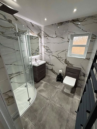 Modern bathroom with marble effect wall tiles a glass shower enclosure