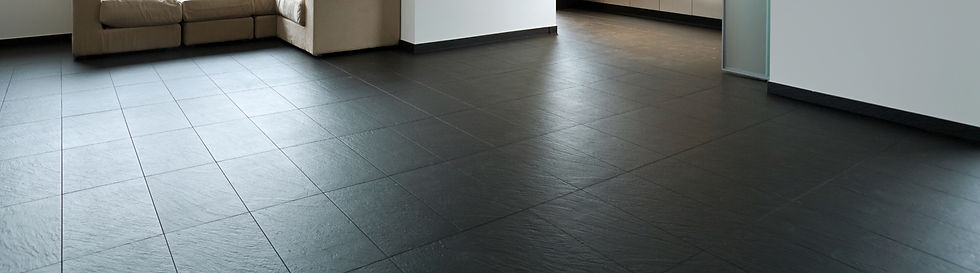 A high-angle shot of large, dark grey or black textured slate floor tiles