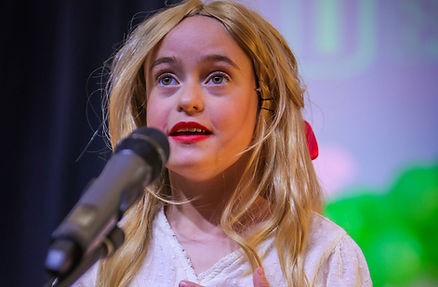 Young girl singing into a microphone on stage