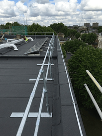 High-angle view of a flat commercial roof fitted with metal safety guardrails