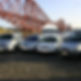 Five silver taxis are parked in a line on cobblestones by the water