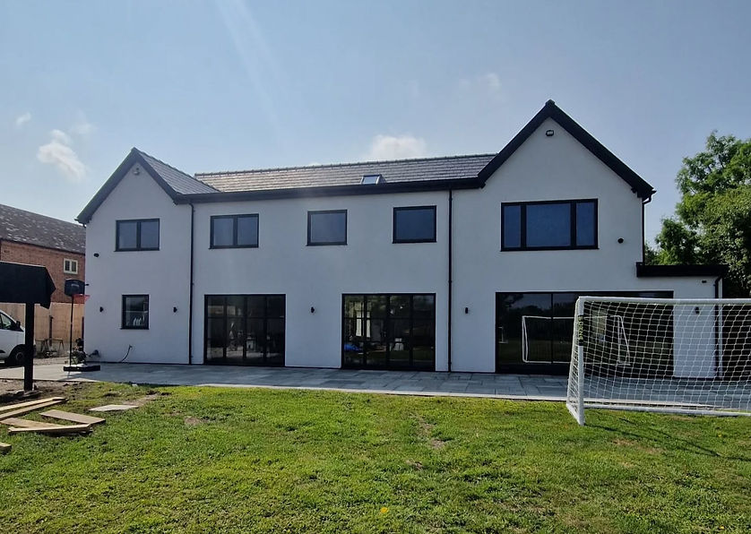 A modern white two-story house with large windows stands under a clear blue sky.