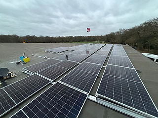 A rooftop is covered with rows of solar panels under a cloudy sky