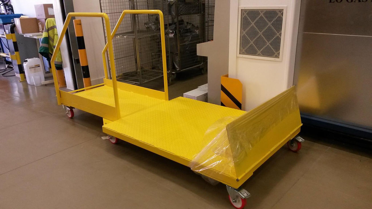 Large yellow industrial warehouse trolley with safety handrails and castor wheels
